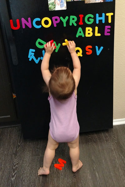 Toddler playing with alphabet letters on the fridge