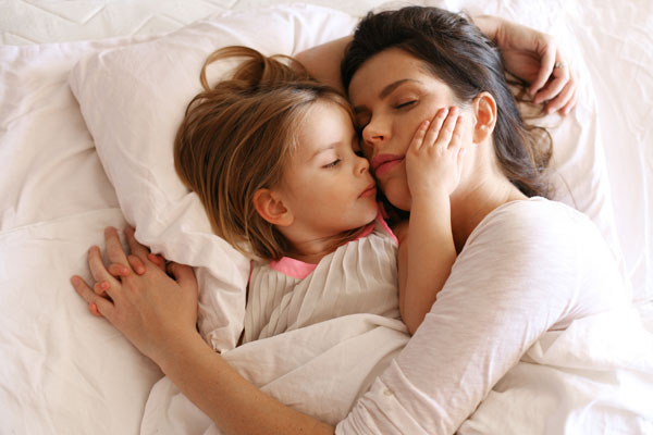 Mother and daughter cosleeping. It is possible to gently help a toddler sleep alone.